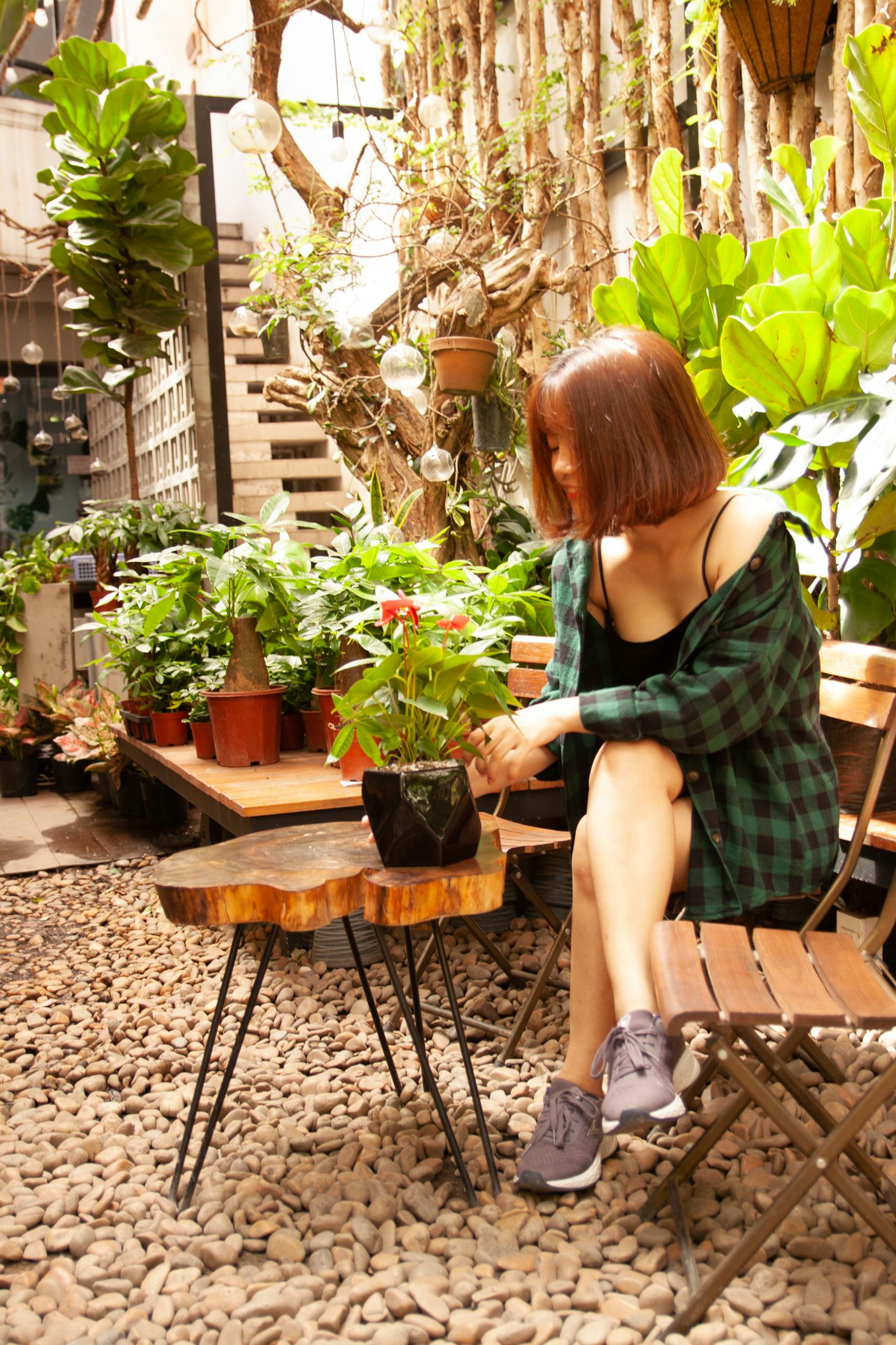 A woman enjoys her time in a lush garden patio filled with vibrant plants.