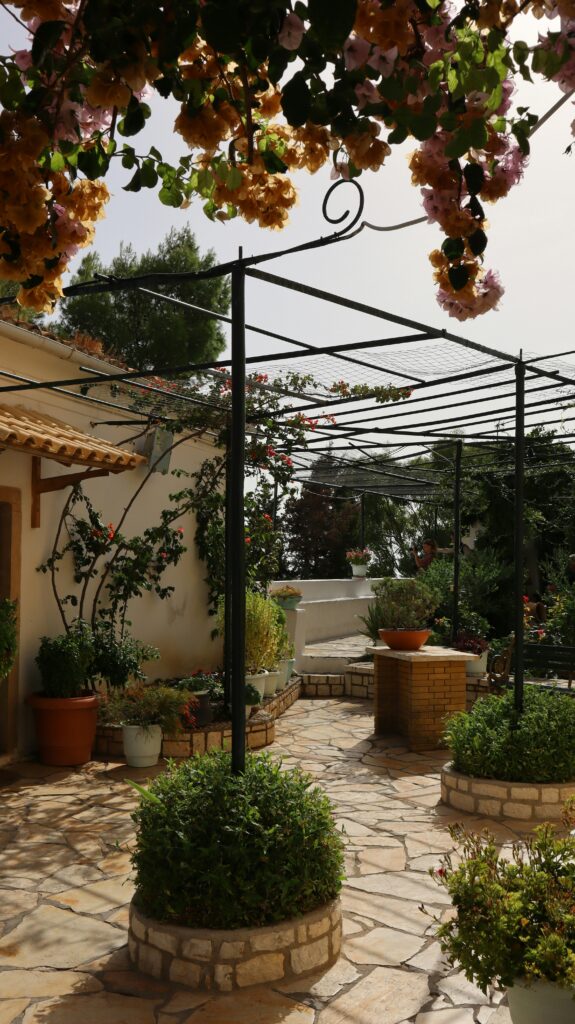 a stone patio with potted plants and a metal pergola—perfect patio ideas for small gardens in uk gardens.